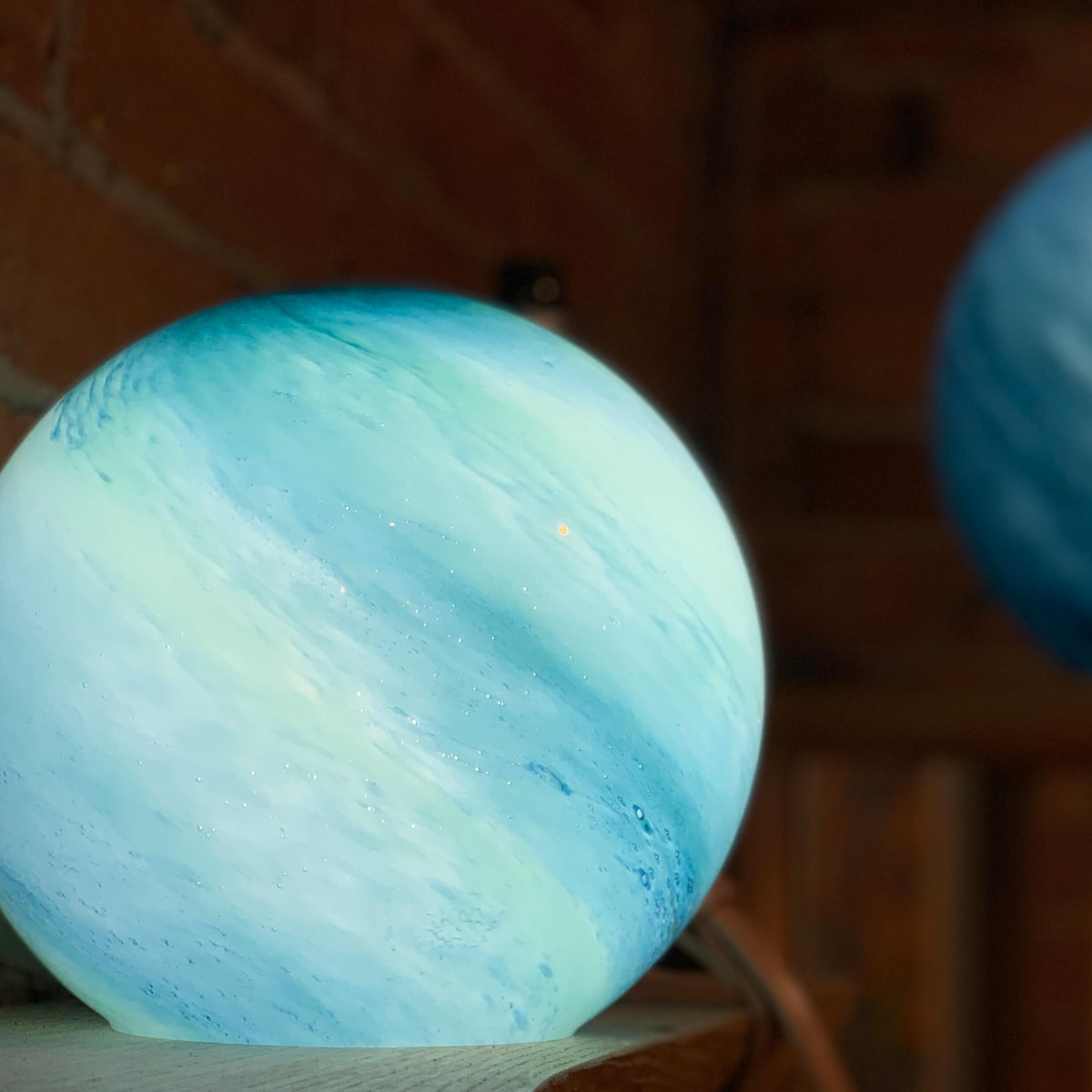 Blue blown glass orb lights, handmade with planet like colouring and a smooth surface. Available at Ferrers Gallery.