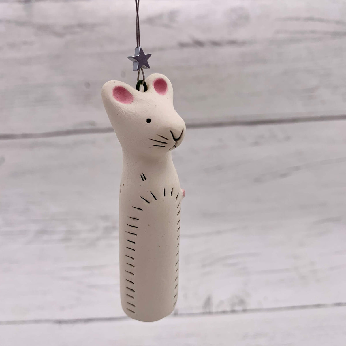 Handmade white ceramic mouse hanging decoration, with a silver star and pink tail.