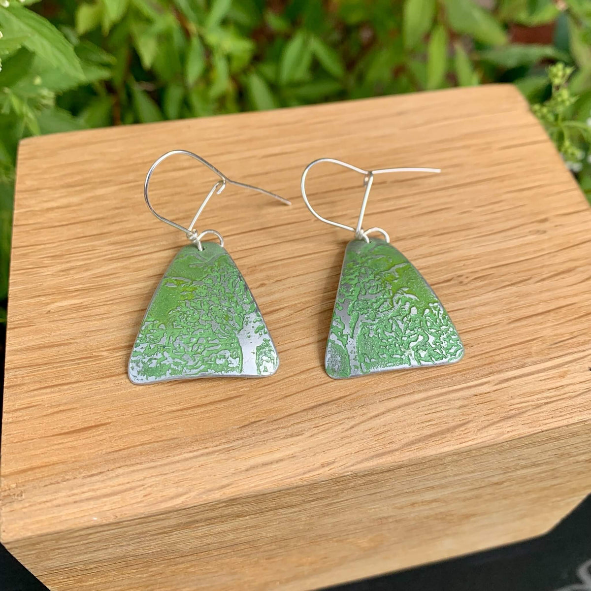Green triangular aluminium earrings with etched tree