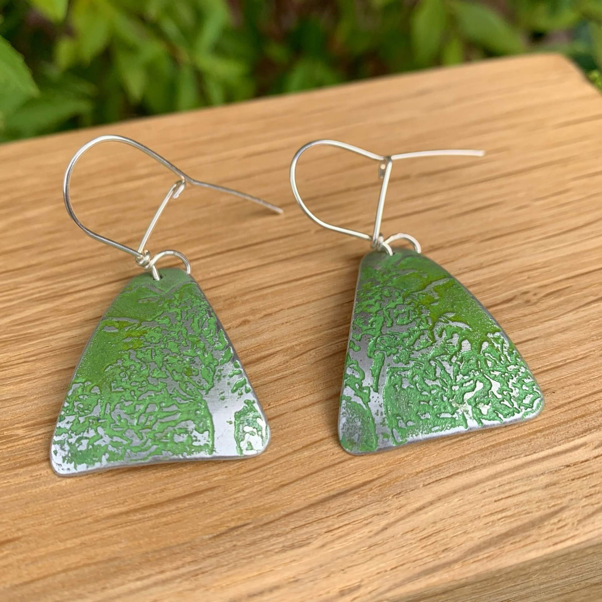 Green triangular aluminium earrings with etched tree