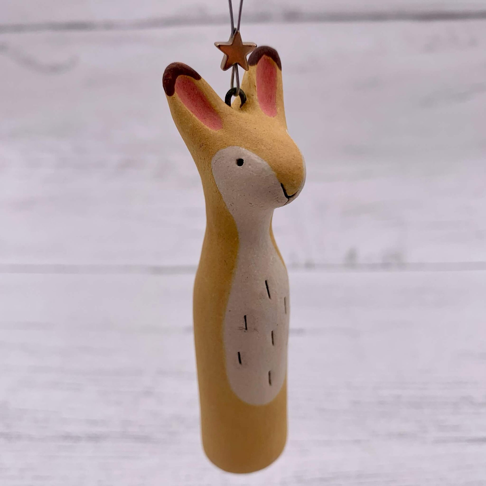 Handmade ceramic hanging of a yellow hare, with a silver star.