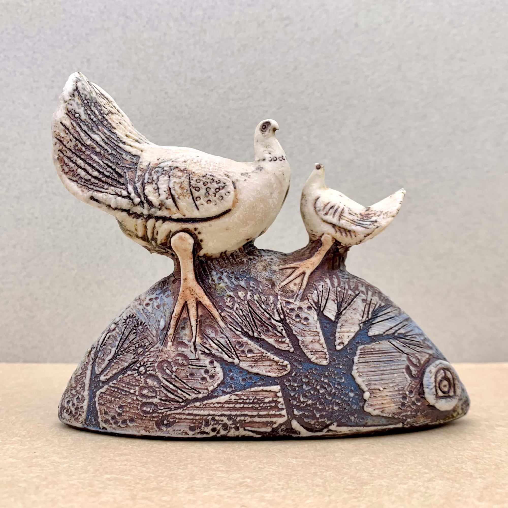 Blandine Anderson handcrafted porcelain sculpture of two doves. Featuring subtle colour contrasts of teal blue, burgundy and porcelain combined with a rich texture on the base and dove wings. Available at Ferrers Gallery.