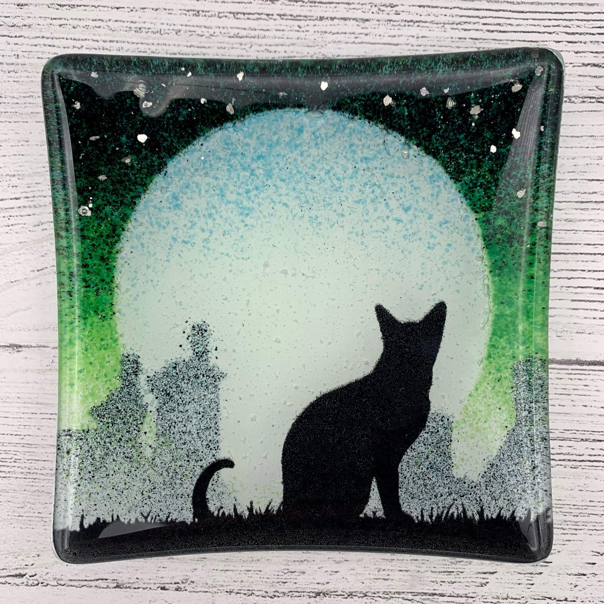 Handmade green fused glass jewellery and trinket dish, featuring a cat silhouette, with a big moon behind and sprinkles of glitter for stars. 
