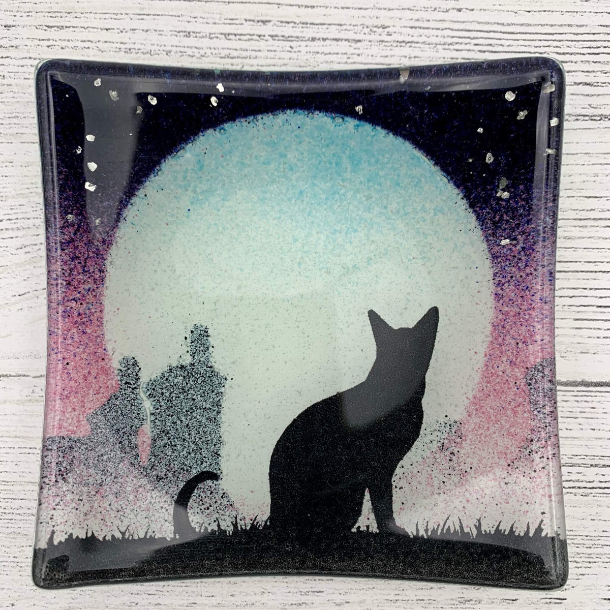 Handmade pink fused glass jewellery and trinket dish, featuring a cat silhouette, with a big moon behind and sprinkles of glitter for stars. 