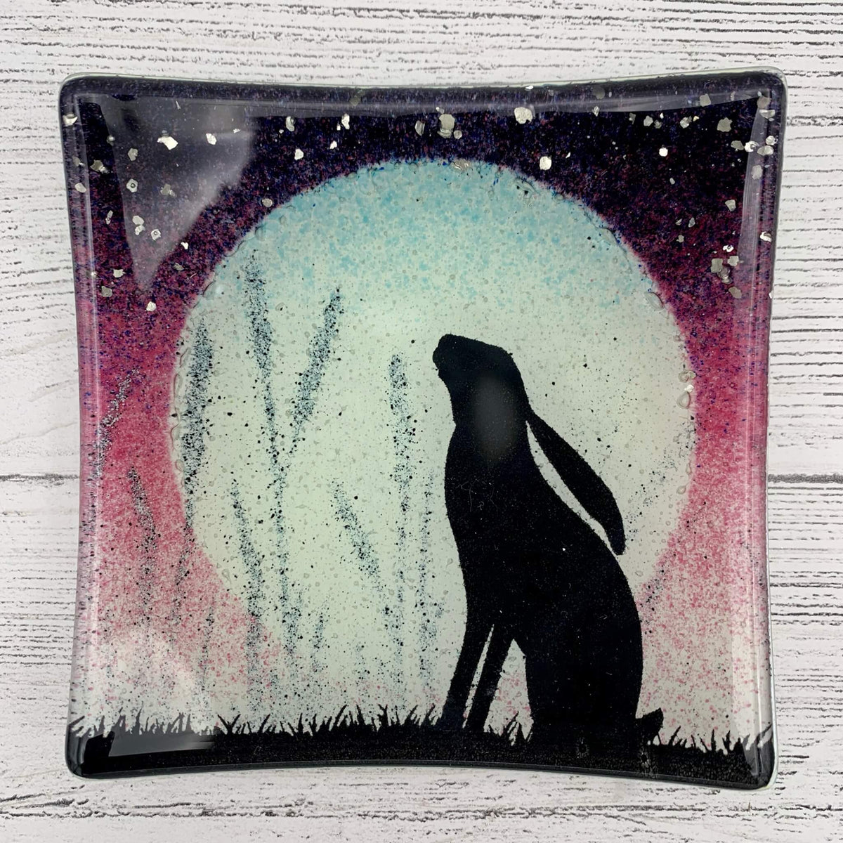 Handcrafted in the uk, fused glass jewellery dish in pink, with a hare silhouette, large moon and glitter for stars.
