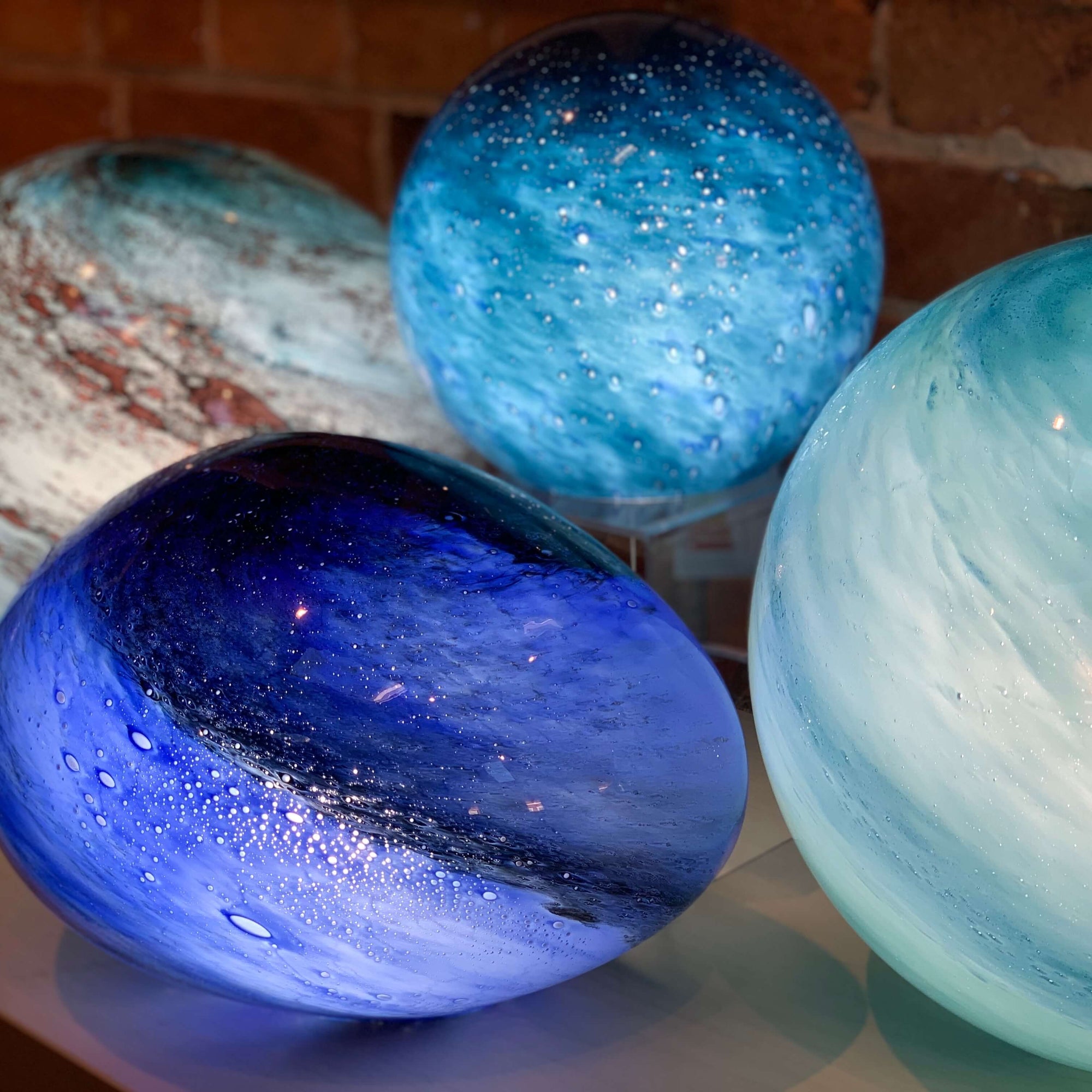 A cluster of our blown glass orb lights, handmade with planet like colouring and a smooth surface. Available at Ferrers Gallery.