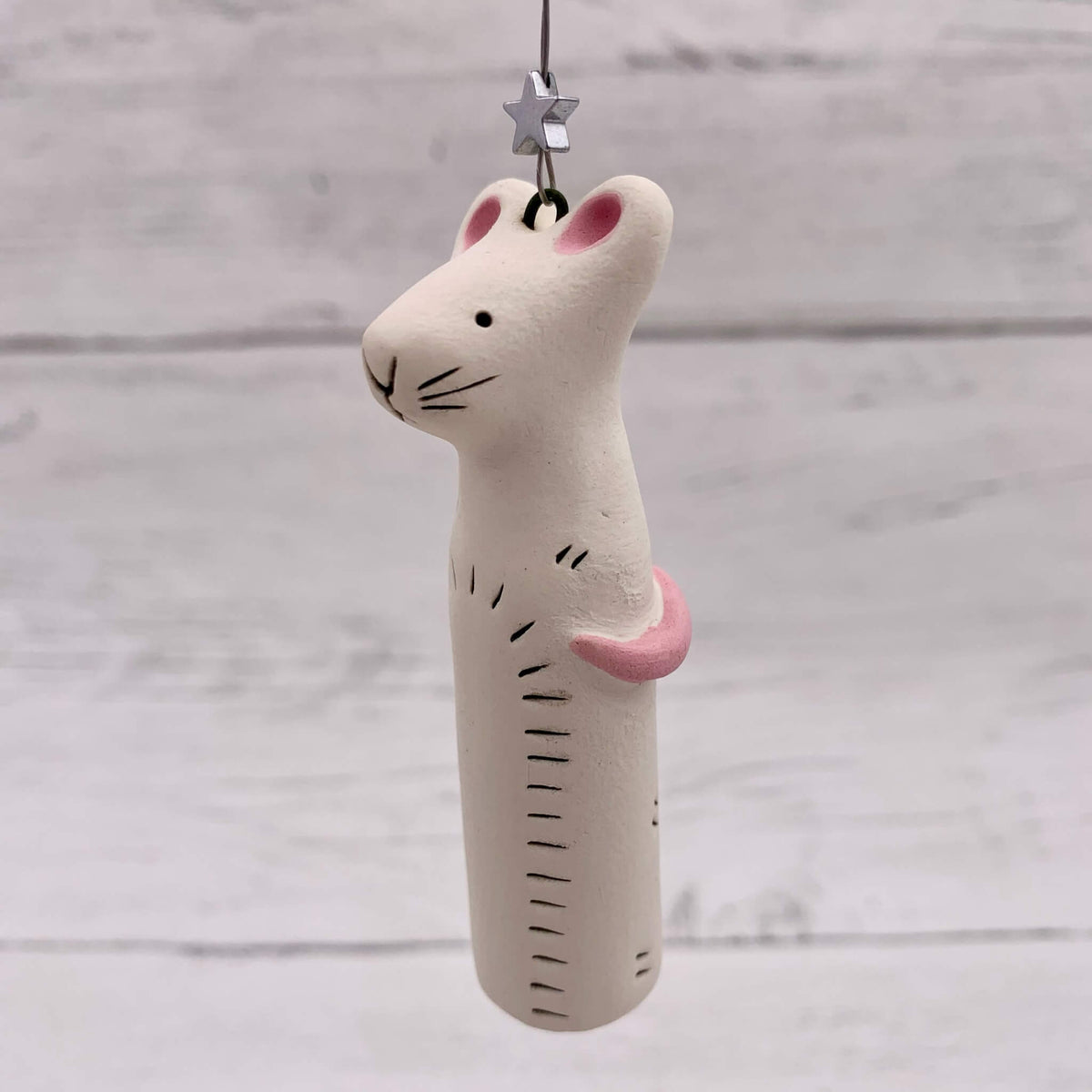 Handmade ceramic mouse hanging, with a silver star and pink tail.