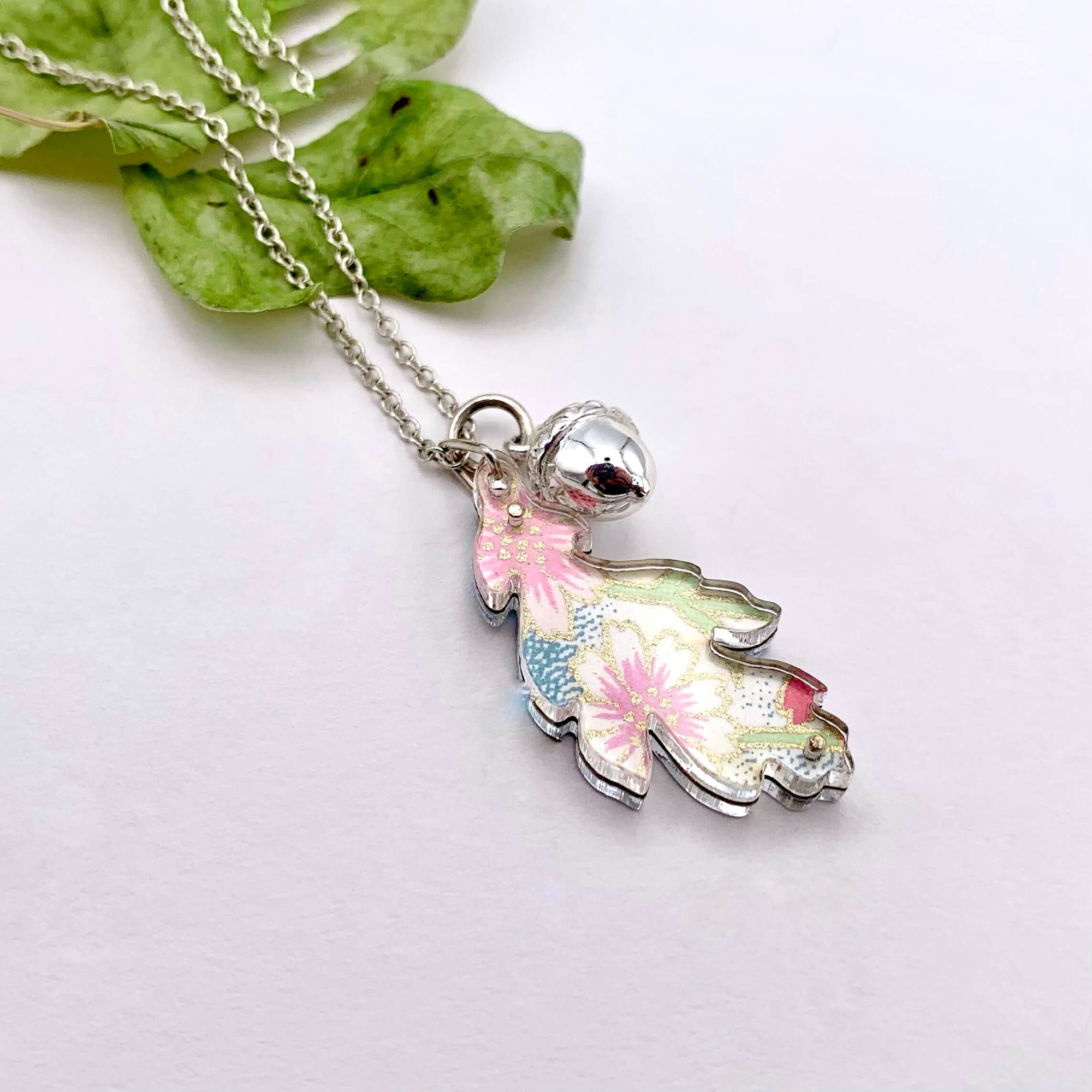 Handmade silver chain necklace, featuring a solid silver acorn and colourful reversible leaf. Leaf is made from pink and blue floral hand-painted paper, between two layers of perspex.