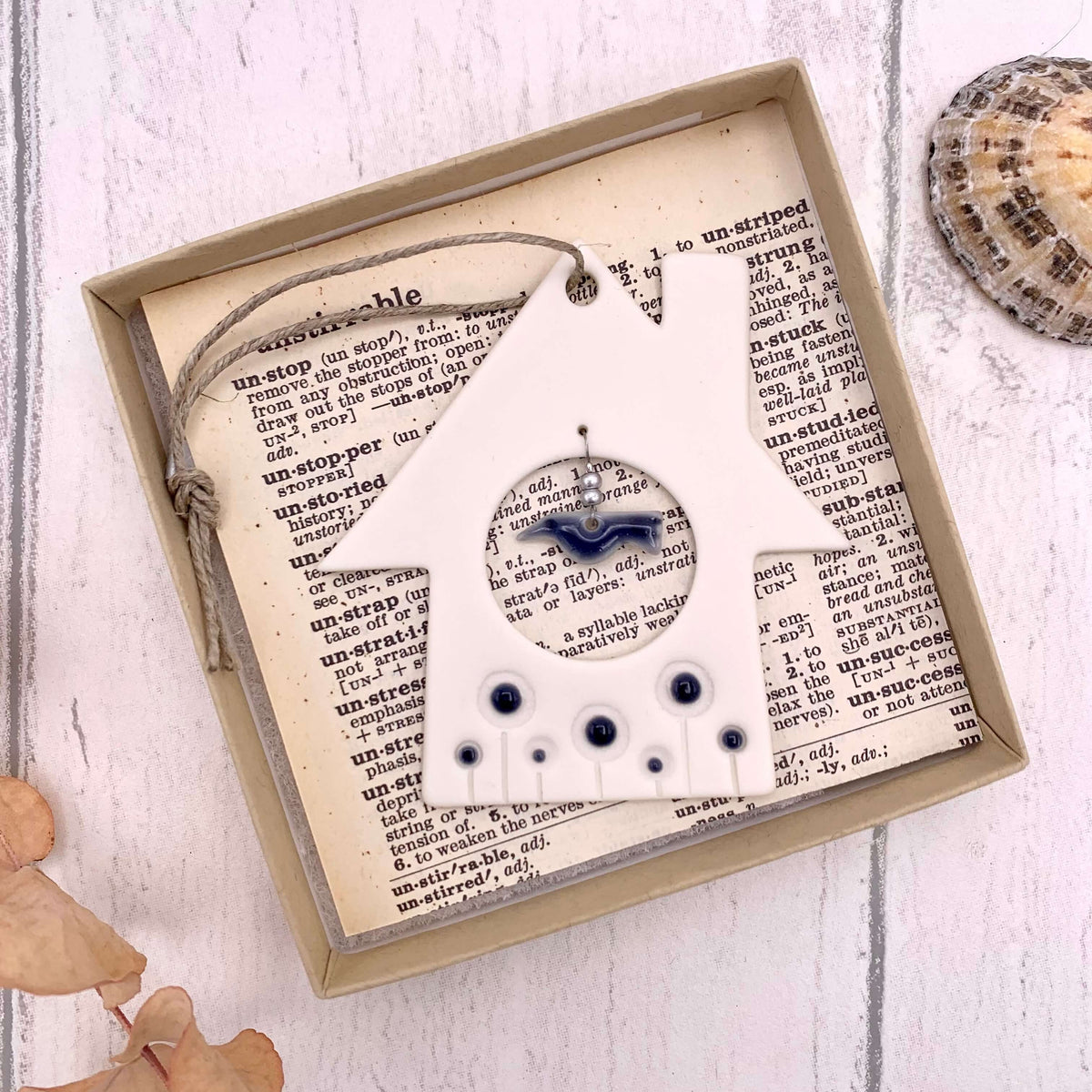 Handmade in the UK, boxed porcelain hanging of a house and bird, with navy glazed detailing on the bird and silver beads.