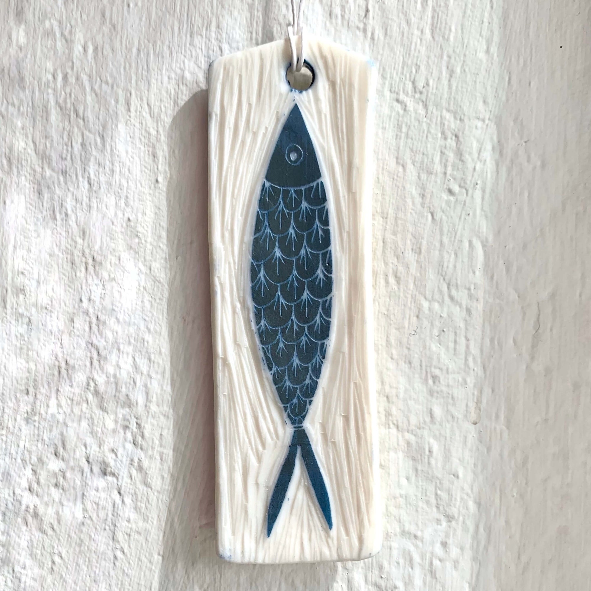 Handmade white porcelain rectangle wall hanging, with hand-carved blue fish with scale details.
