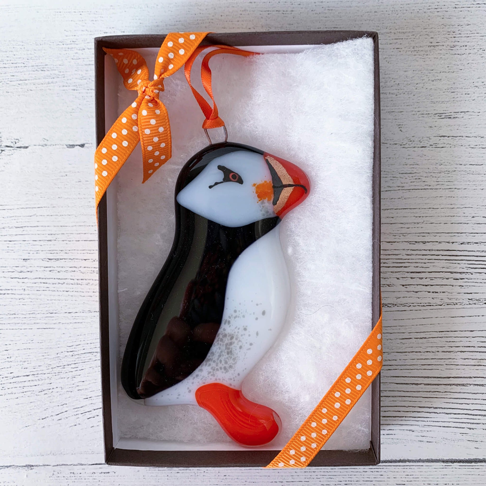Handmade Boxed Fused Glass Puffin hanging, by Sarah Myatt. With orange spotted ribbon on box.