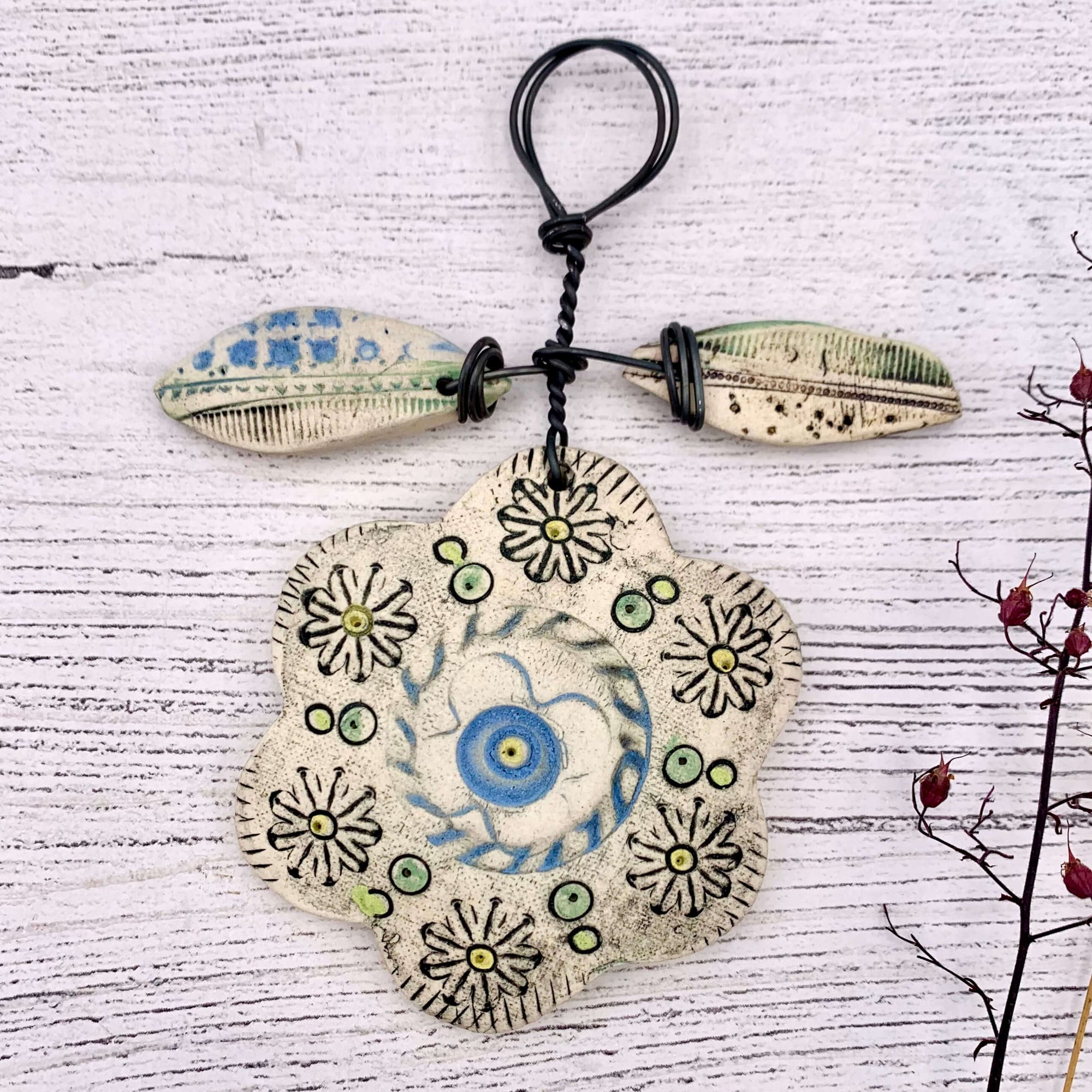 Shirley Vauvelle handmade ceramic flower hanging decoration, made with wire and ceramic. Each flower is made individually, this piece has flower patterns carved in and blue, green and yellow glazing.