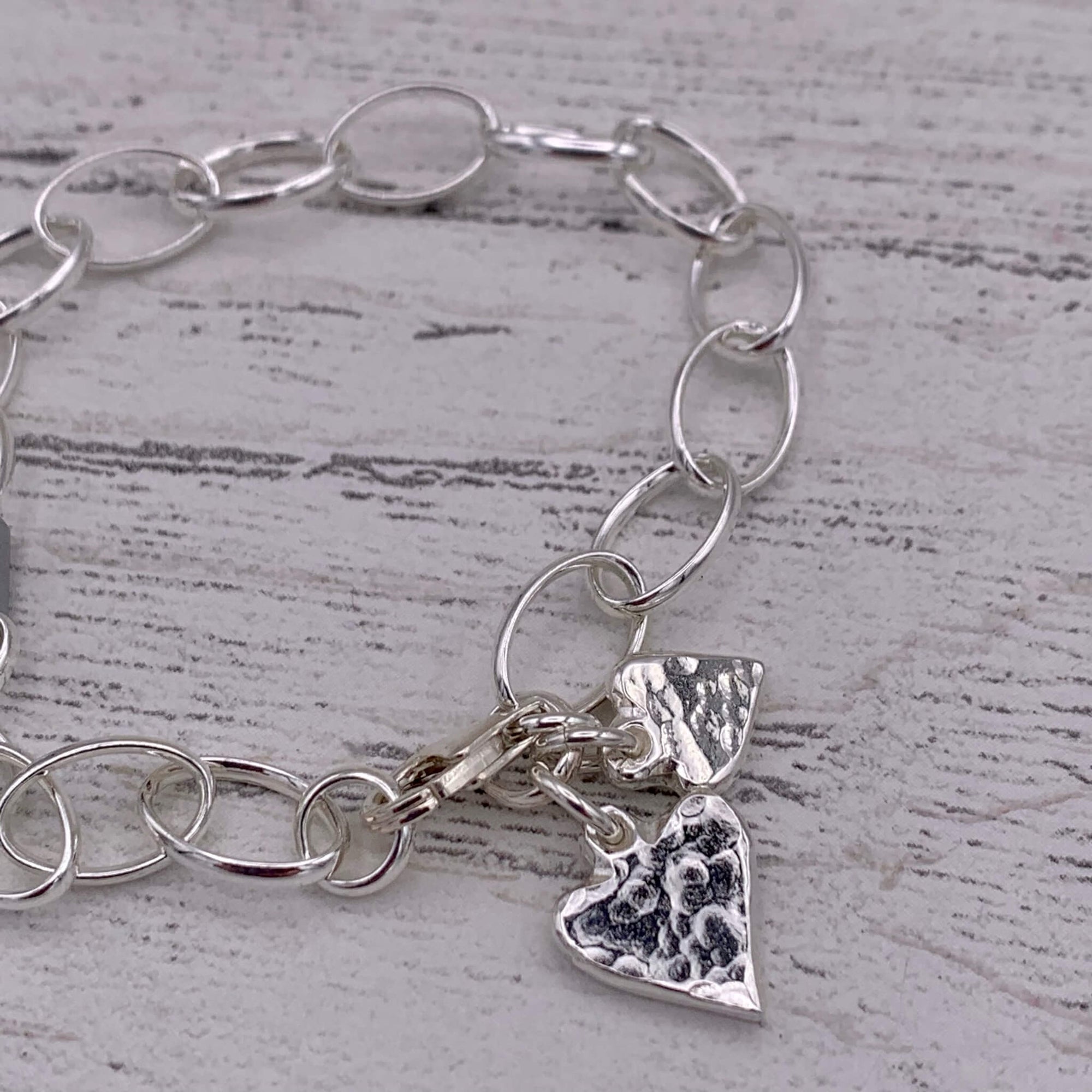 Handcrafted sterling silver chain bracelet, with two small textured hearts.
