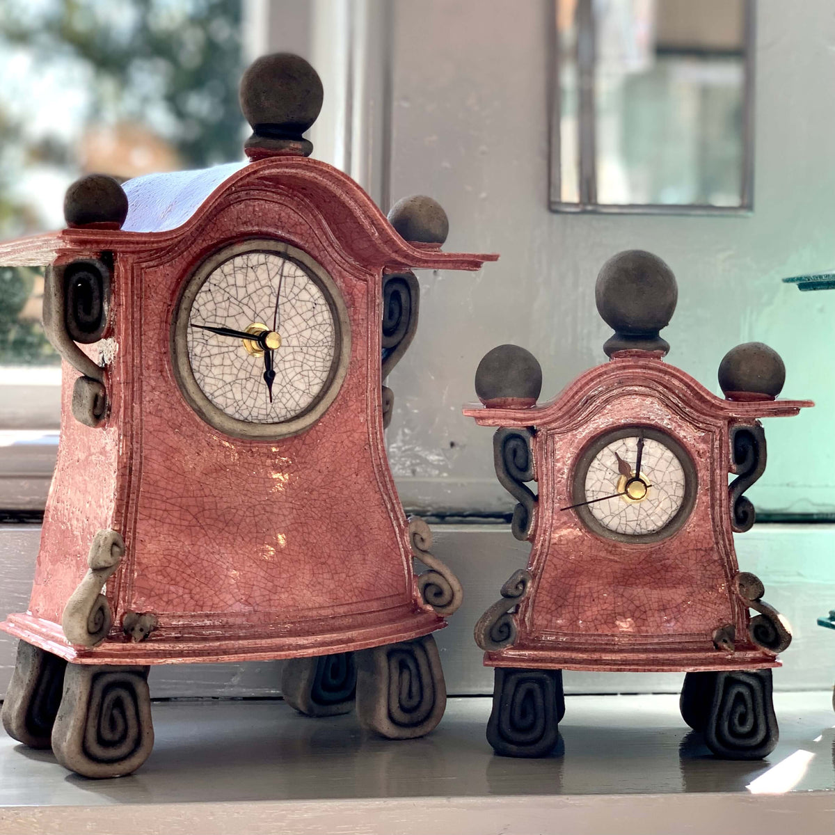 Smaller and larger pink ceramic raku fired clocks.