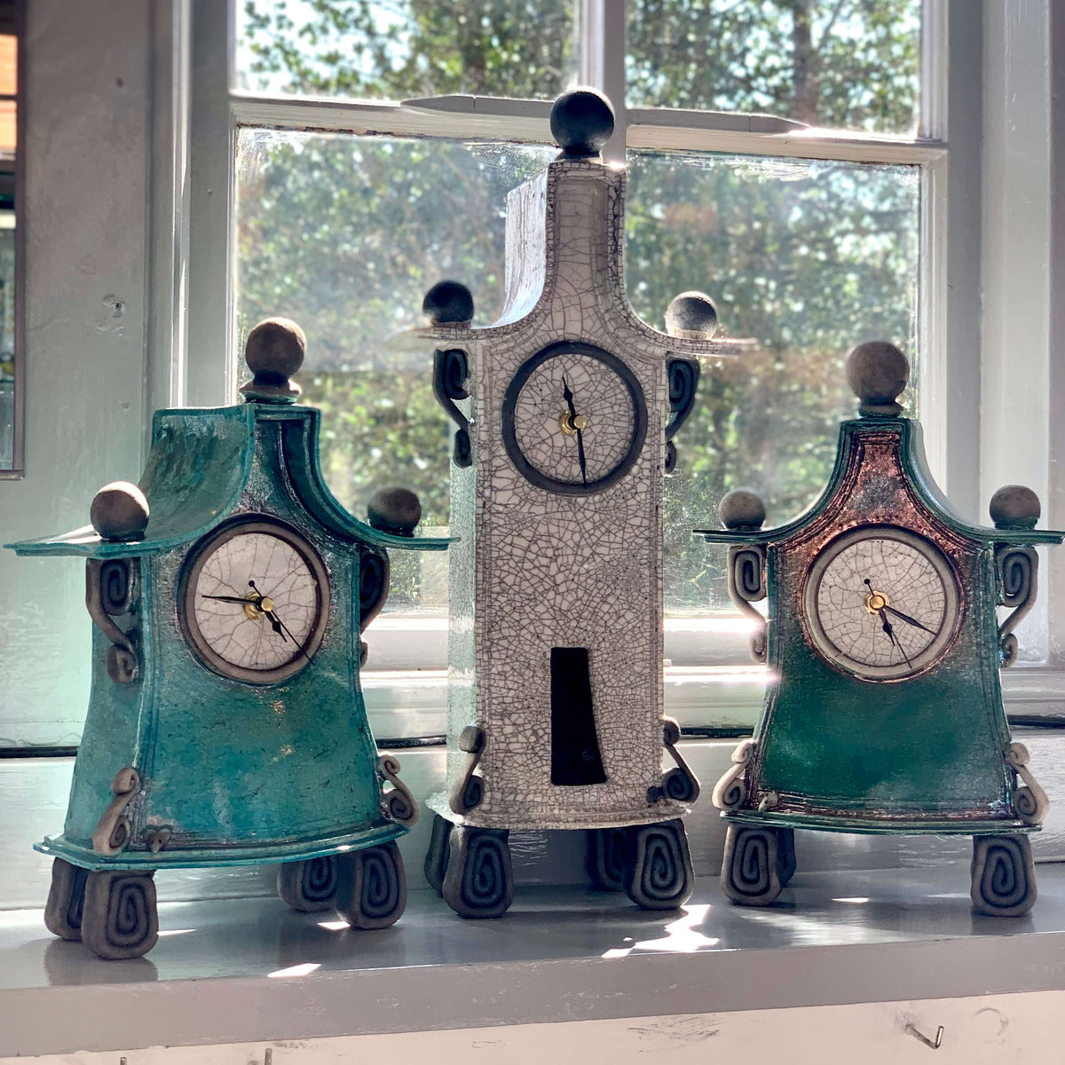 Three large ceramic raku fired clocks, in green and white.